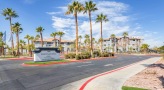entrance to a parking lot with a sign and palm trees