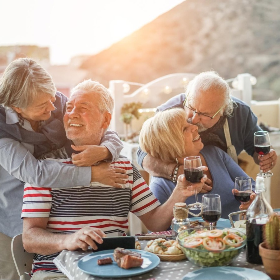 Your new home is waiting a group of people at a table eating with the sun in the background