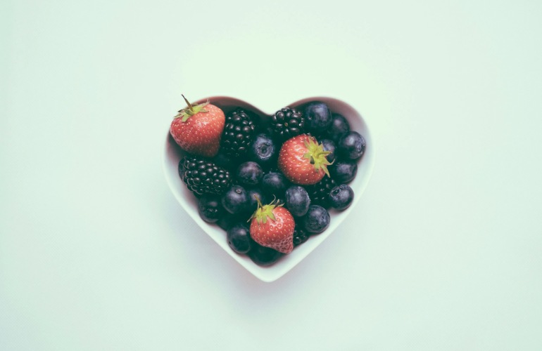 Heart-shaped bowl containing different berries.