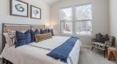 Large well lit bedroom with carpeted floors and a large window 