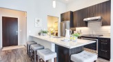 Spacious and well lit kitchen with stainless steel appliances and dark accents 