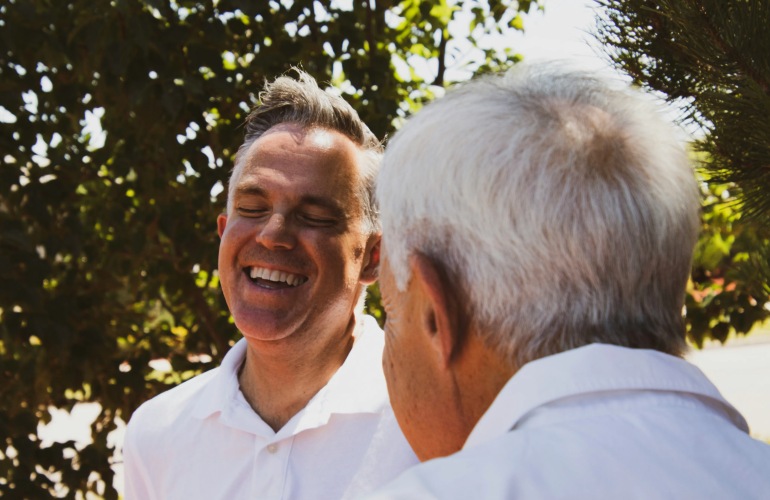 An adult man talks to his senior adult father.