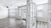 Spacious and well lit living room with wood floors and a large window