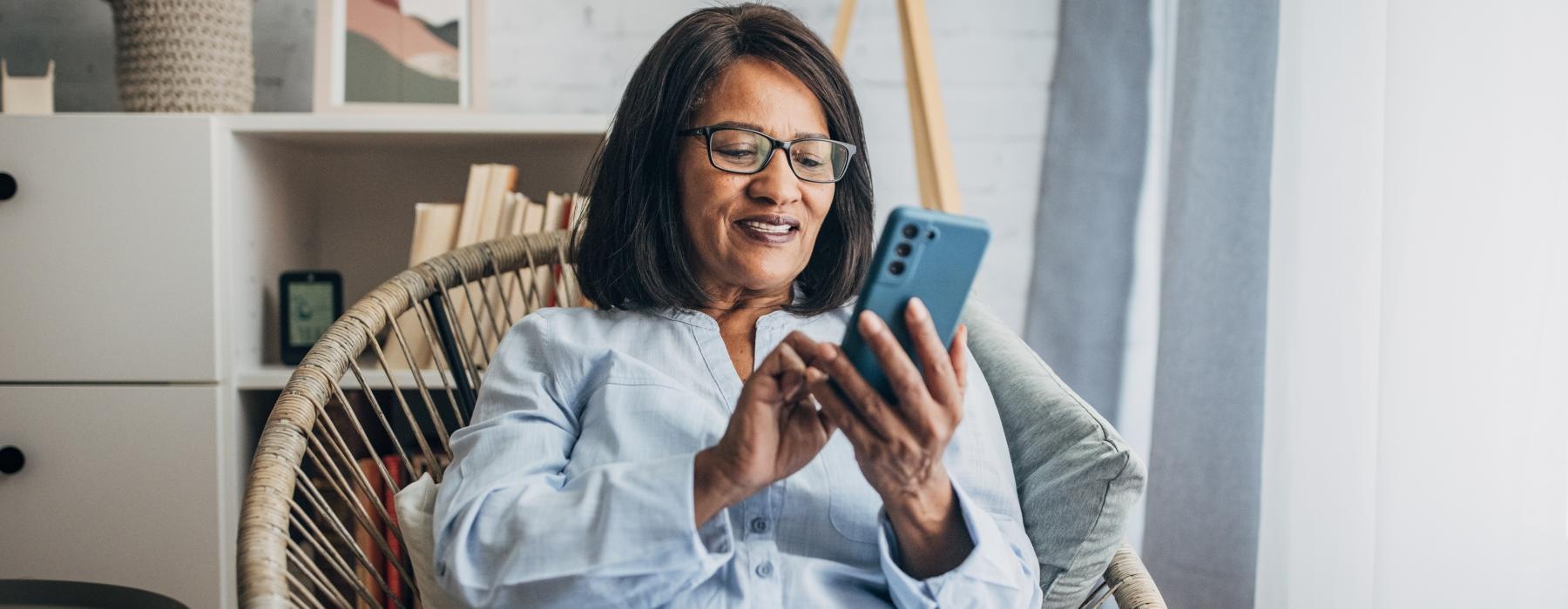 Woman sitting by a window on her phone smiling