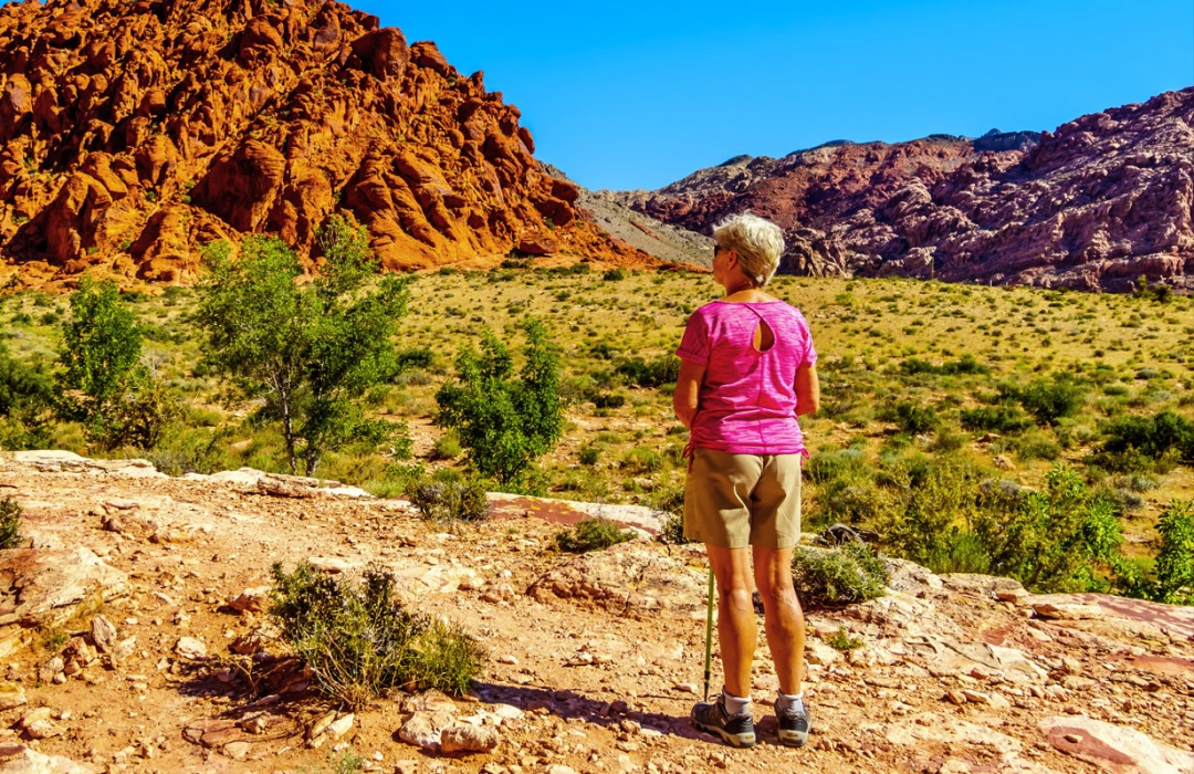 Senior woman stands and enjoys the scenery of mountains in a desert.