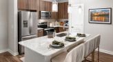 Spacious and well lit kitchen with stainless steel appliances and dark accents 