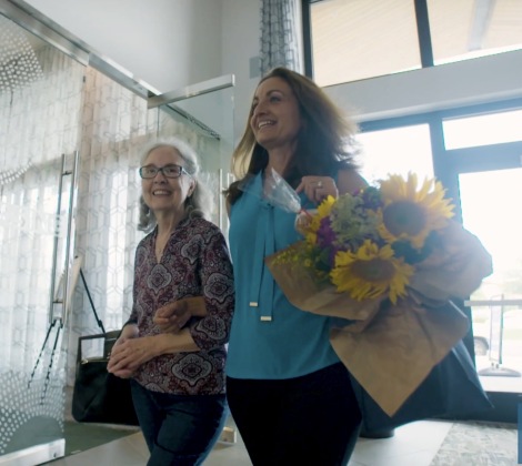 Daughter and mother walking into an Overture lobby with flowers