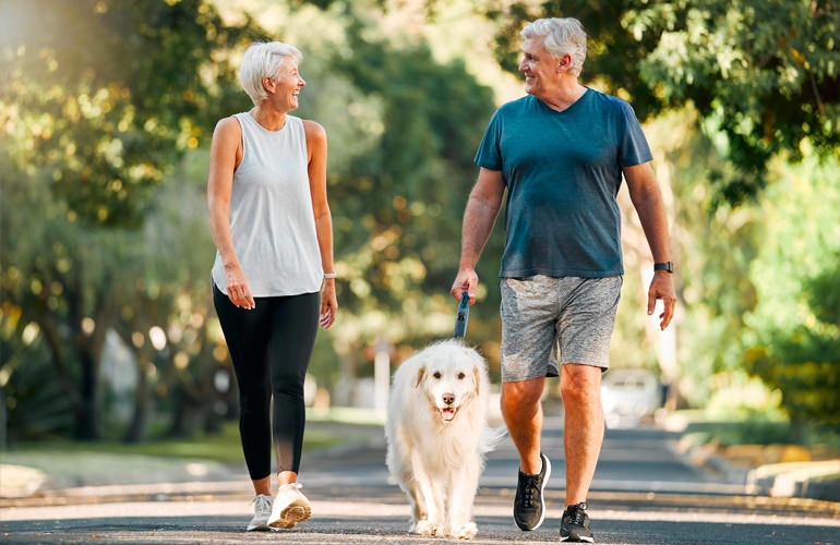 Senior couple walking their dog in a residential neighborhood.