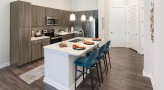 Spacious and well lit kitchen with stainless steel appliances and dark accents 