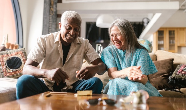 a couple laughing while sitting on a couch indoors