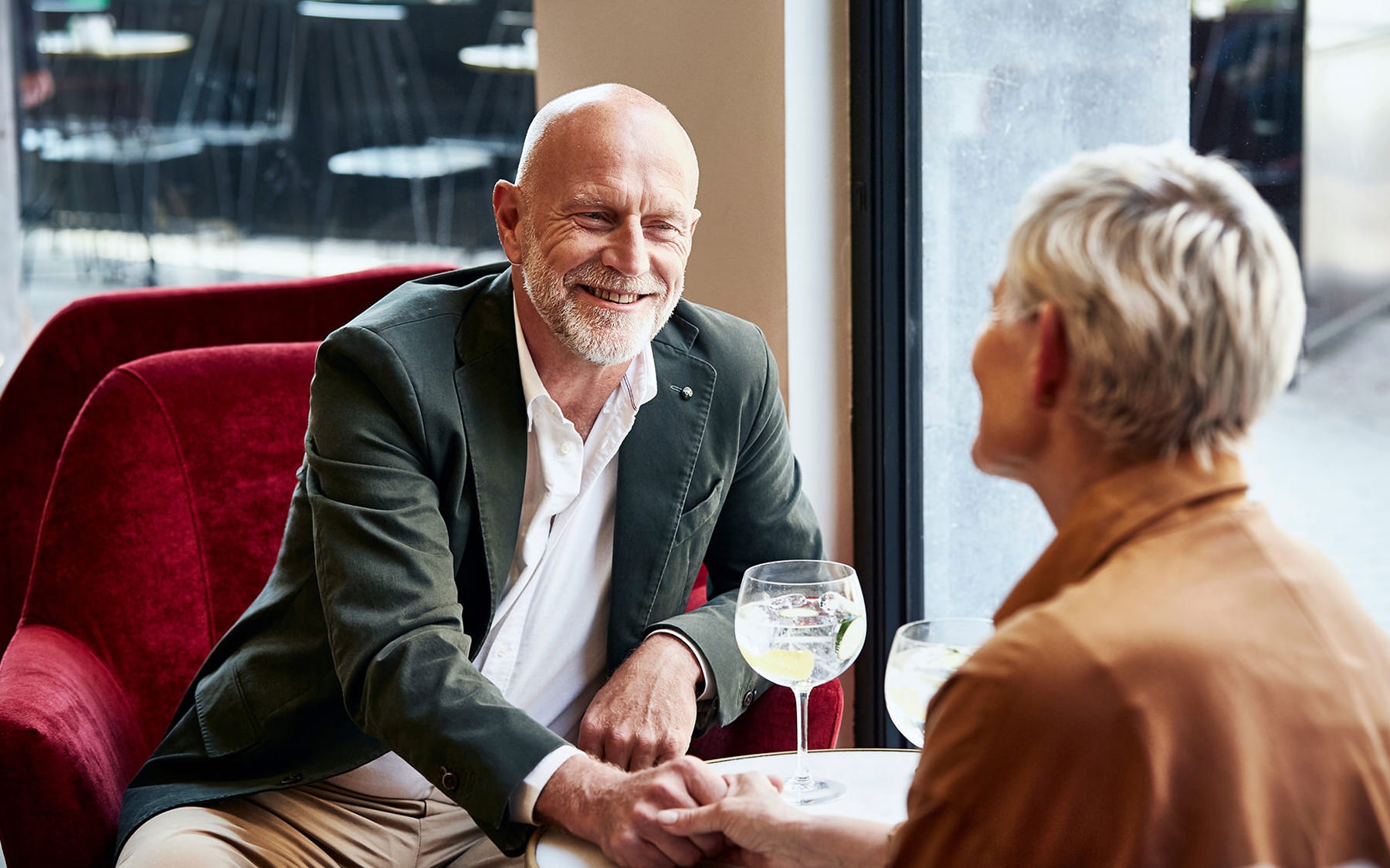 man and woman sitting across from each other drinking wine