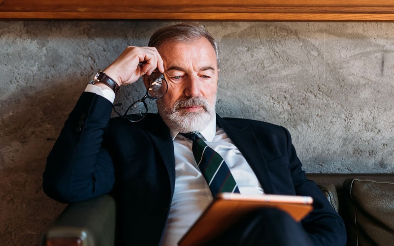 Nearby Activities & Attractions man in suit sitting in chair looking at a tablet device