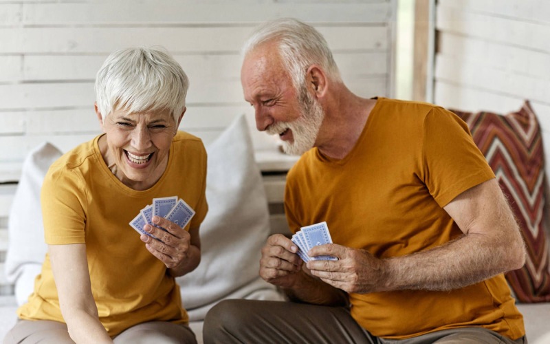 elderly couple laughing and playing cards together