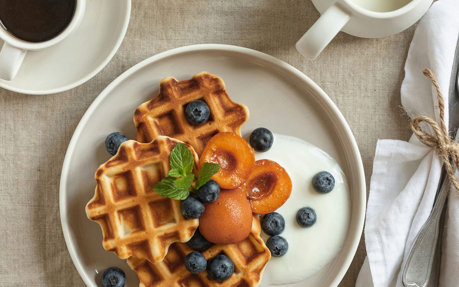 table of food with waffles, fruit, and coffee