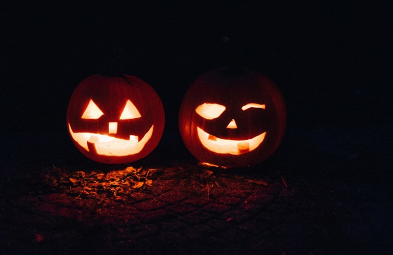 two pumpkins carved with lights