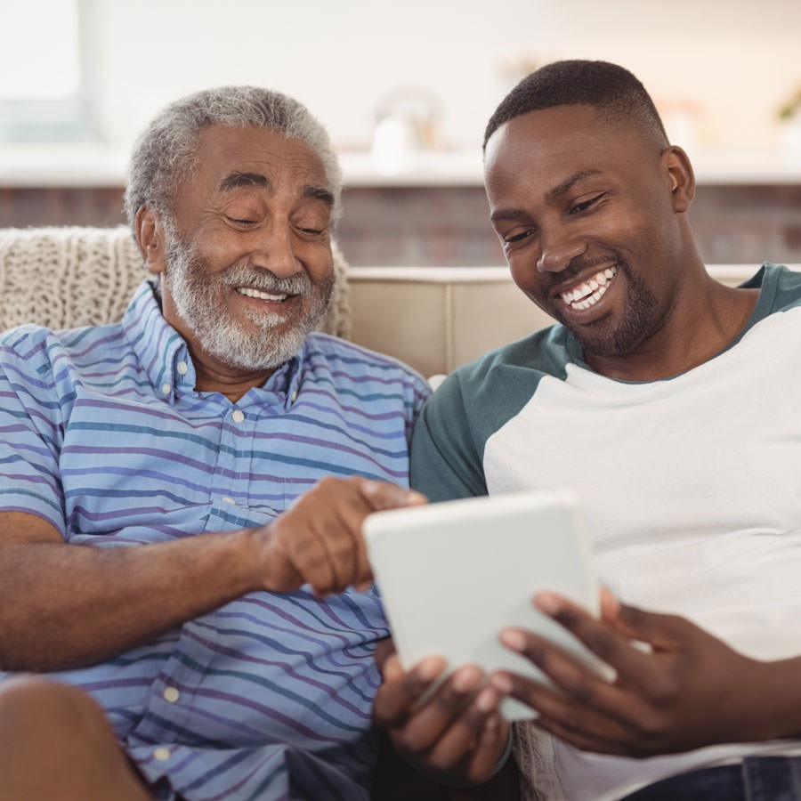 Grandpa and grandson sitting on a couch looking at a tablet