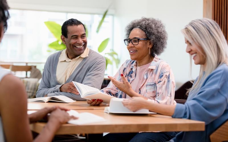 a group of people sitting around a table with books