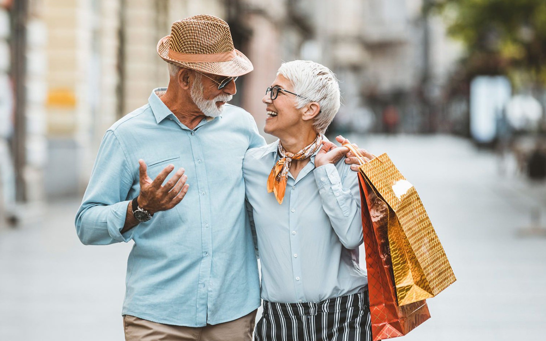 man and woman walking down street with shopping bags
