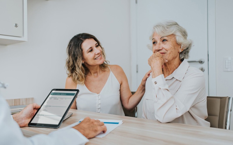 Nearby Activities & Attractions Two people in a doctor's office at Overture Dr. Phillips in Orlando, FL, featuring a health care worker holding a tablet.