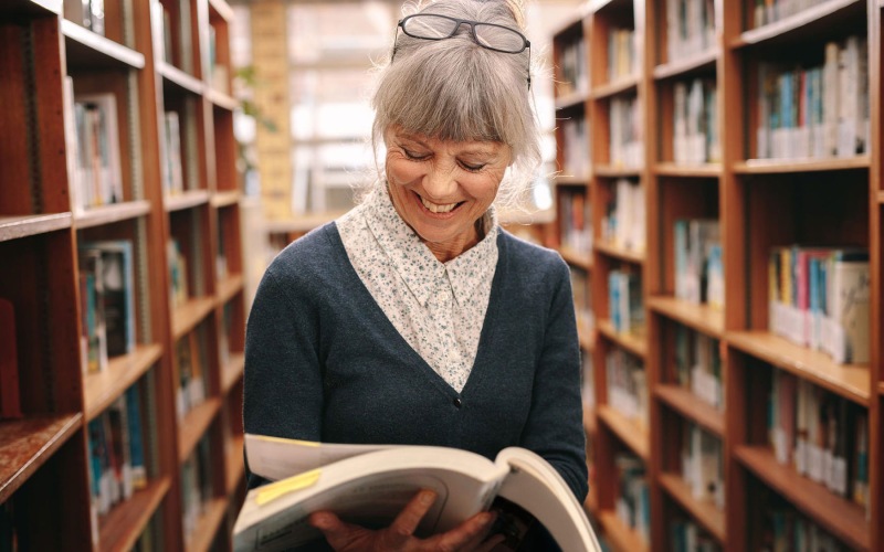 woman standing reading a book in a library