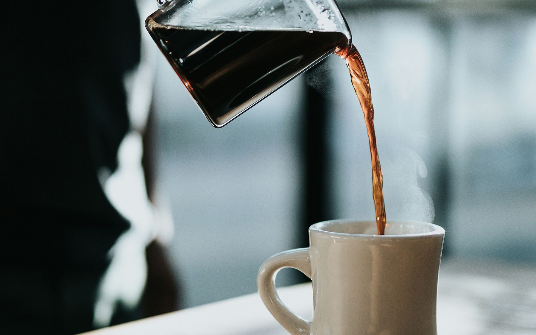 clear coffee carafe pouring into a coffee mug
