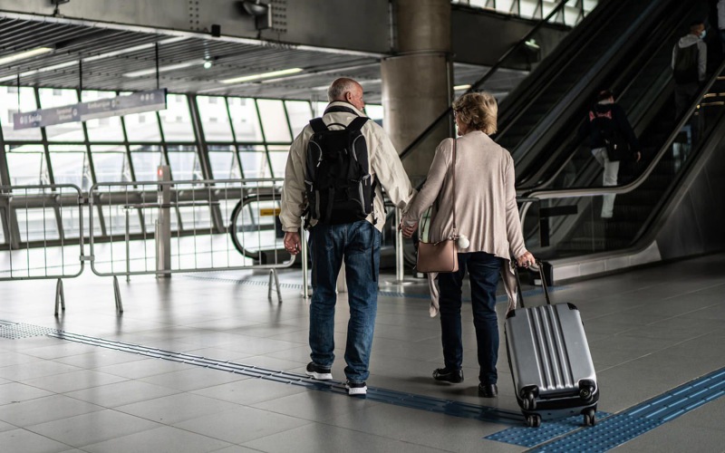 Couple walking in an airport with luggage in tow