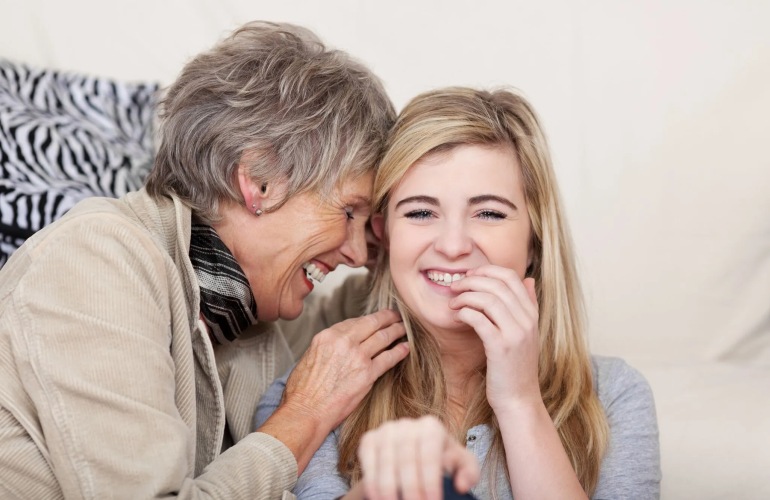 A senior mother and her daughter talking and laughing.