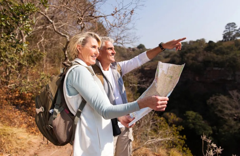 A senior adult couple holding a map while hiking.