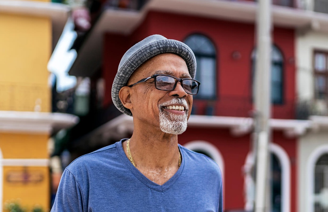 A senior man wearing a hat walks in a downtown area in South Carolina.