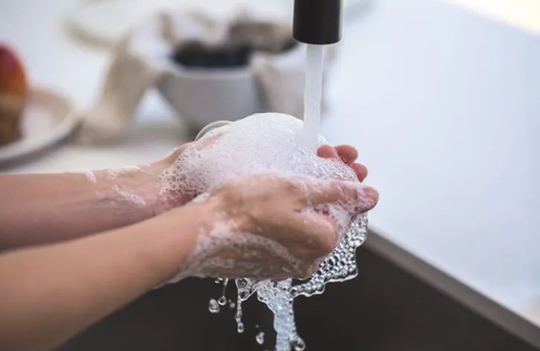 Close up image of hands being washed over a kitchen faucet.