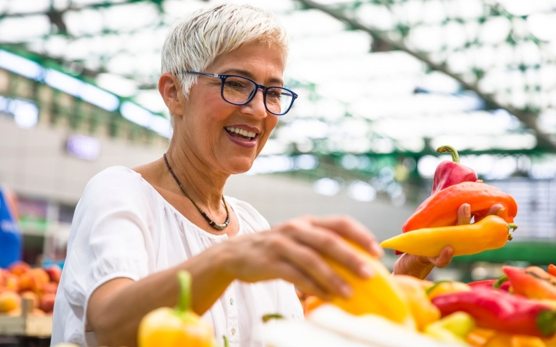 Vibrant community life with a variety of dining options a woman smiling and holding a bunch of vegetables
