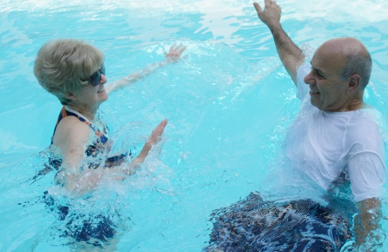 Senior couple swimming together in a pool.