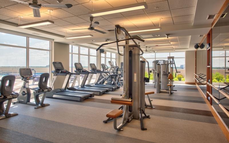 Large fitness center with ample machines and wood floors