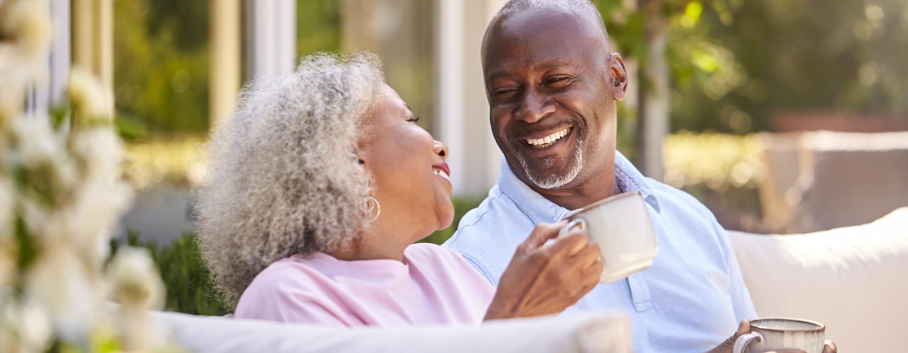 Couple sitting outside drinking coffee and laughing 