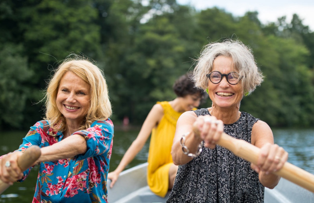 Senior women row in a boat along a river in Texas.