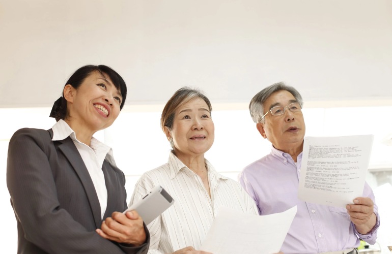 A senior adult couple look at a property with their real estate agent.