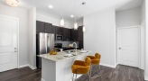 Spacious and well lit kitchen with stainless steel appliances and dark accents 