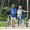 a man and woman walk their bicycles through park