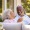 a man and woman sit outside on a couch and smile at each other