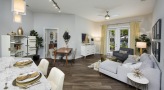 Spacious and well lit living room with wood floors and a large window