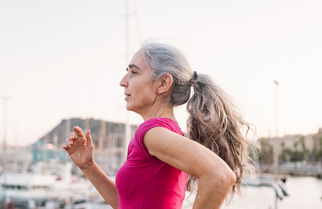 A senior woman jogs along a pier by the river in Virginia.