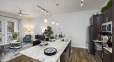 Spacious and well lit kitchen with stainless steel appliances and dark accents 