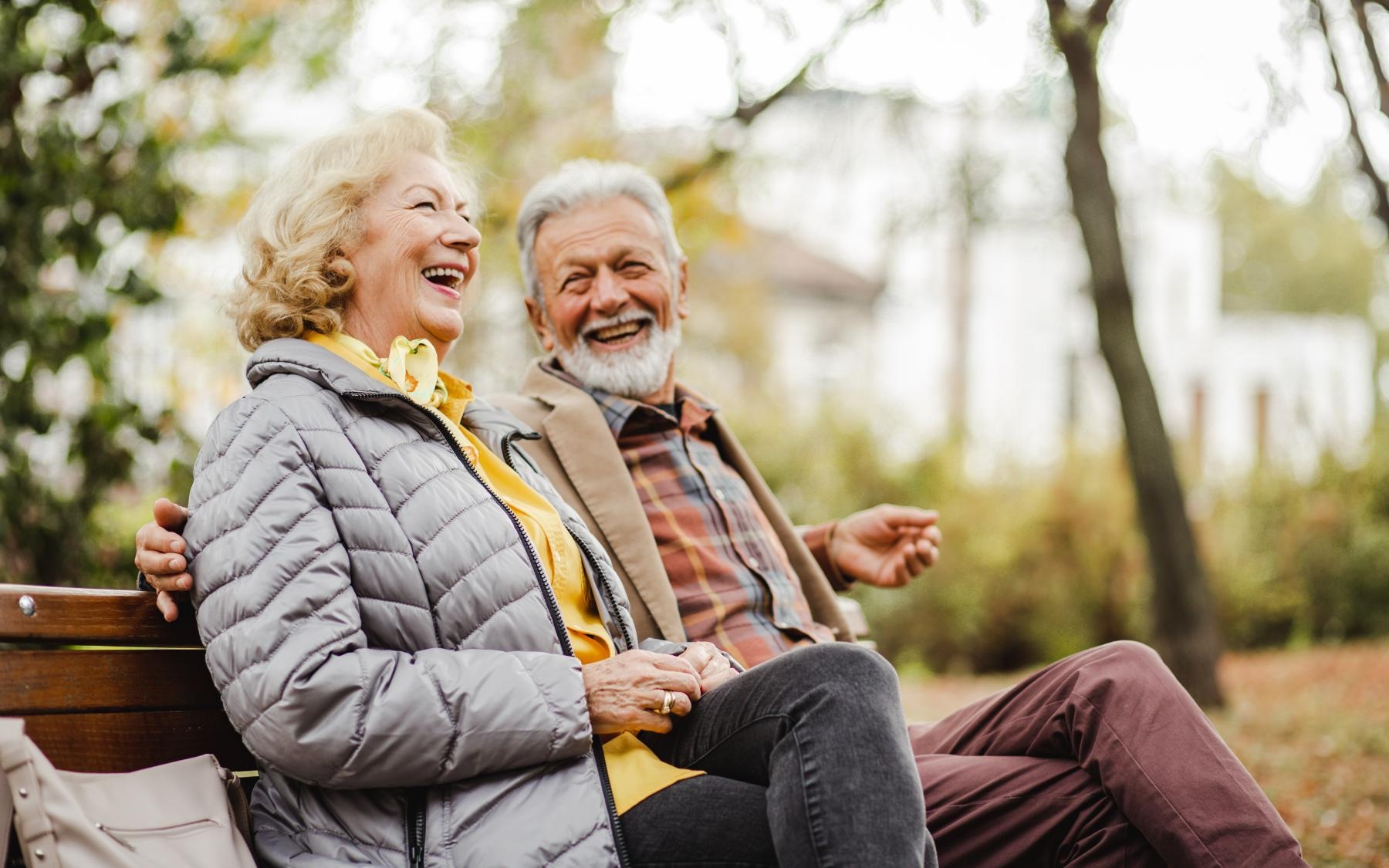 Lifestyle Couple sitting and smiling on a bench in the park