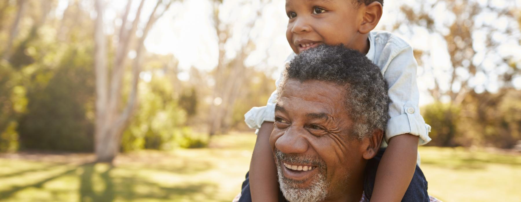 Child sitting on his grandfathers shoulders 