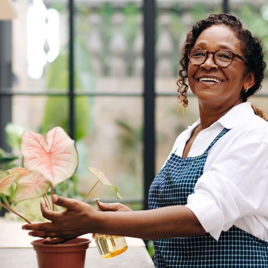 woman smiling as she waters a plant